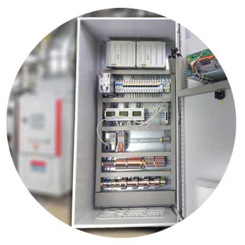 Ein offenes industrielles elektrisches Schaltpult mit verschiedenen Kabeln, Leistungsschaltern und elektronischen Komponenten, die ordentlich in einem Metallschrank angeordnet sind. Der Hintergrund ist unscharf.