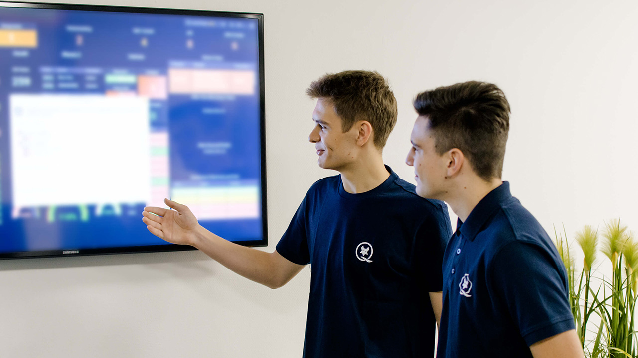 Ein LEITDESK-Techniker zeigt einem anderen etwas auf einem blauen Bildschirm